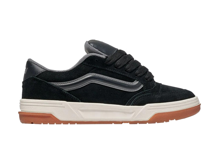 Tenis Vans negros con franja gris, entresuela blanca y suela de goma color caramelo.