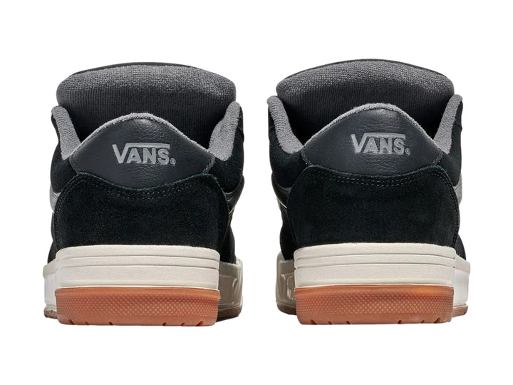 Tenis Vans negros con franja gris, entresuela blanca y suela de goma color caramelo.