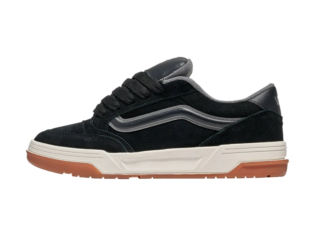 Tenis Vans negros con franja gris, entresuela blanca y suela de goma color caramelo.