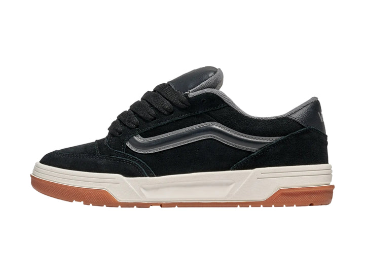 Tenis Vans negros con franja gris, entresuela blanca y suela de goma color caramelo.