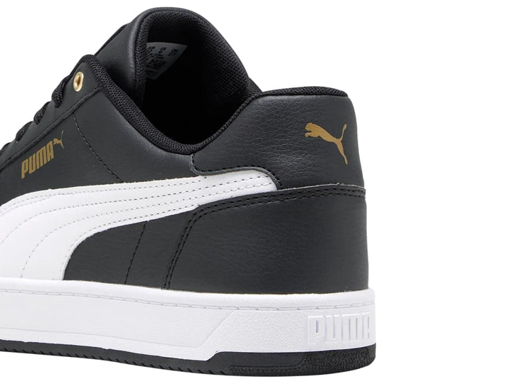 Tenis PUMA Caven 2.0 color negro con franja y suela blanca y detalles dorados.