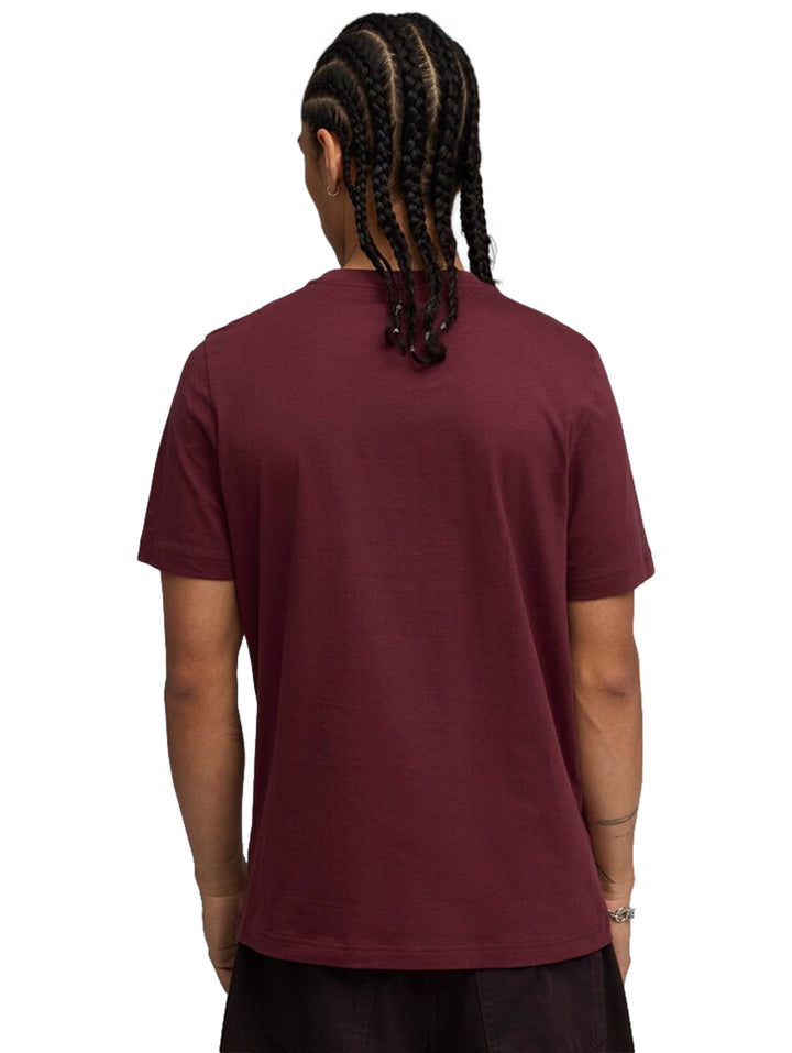 Hombre vistiendo camiseta PUMA color rubí con logotipo blanco en el pecho.