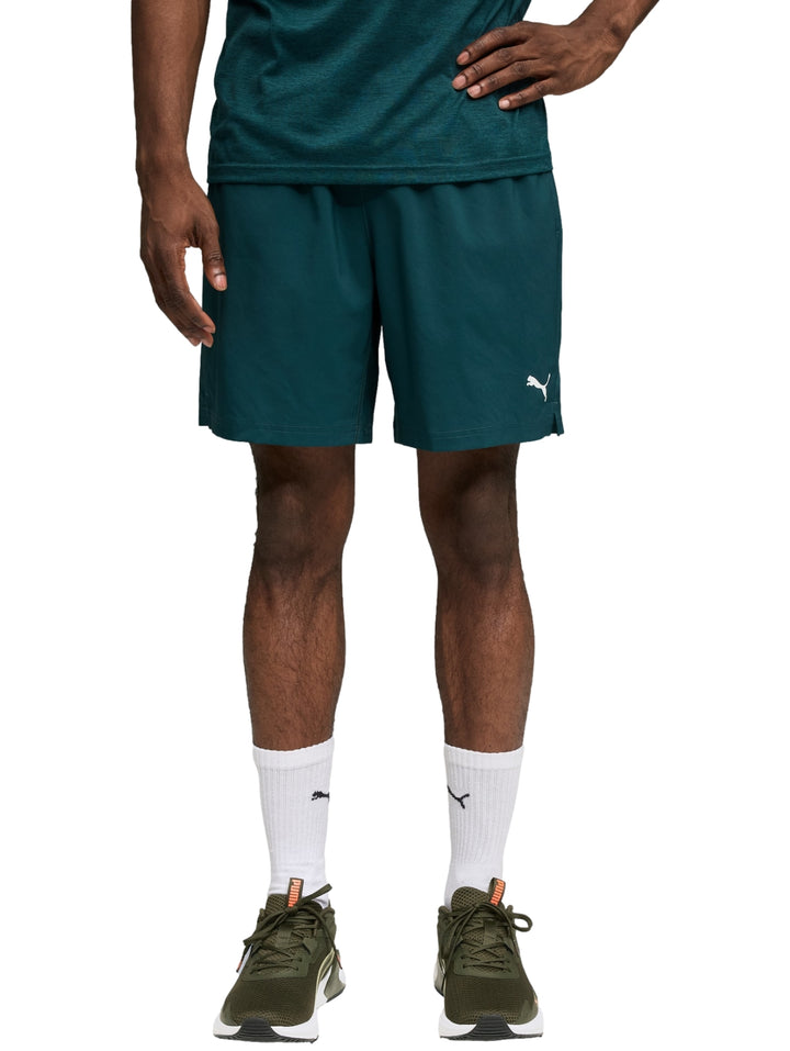 Hombre vistiendo shorts deportivos PUMA en color verde oscuro Green Terrain.
