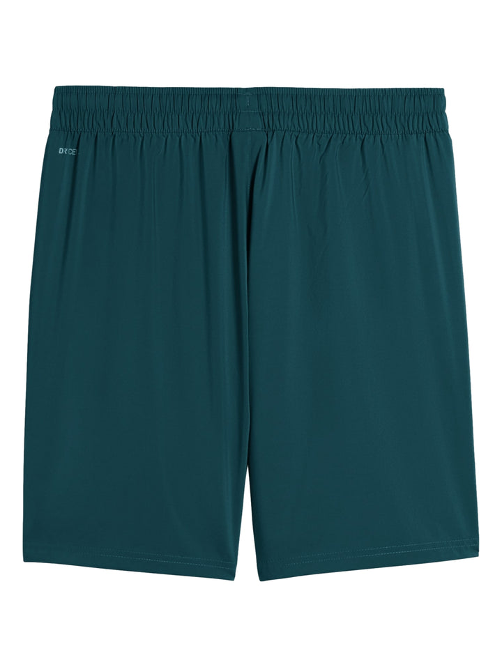 Hombre vistiendo shorts deportivos PUMA en color verde oscuro Green Terrain.