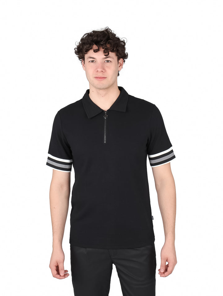 Hombre vistiendo playera polo negra con cierre y rayas blancas y grises en las mangas.