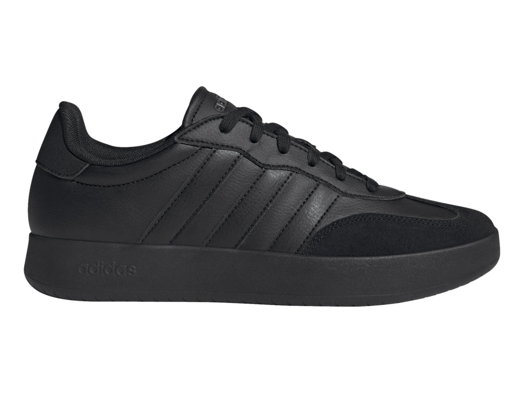 Tenis Adidas color negro con tres franjas laterales y suela plana.