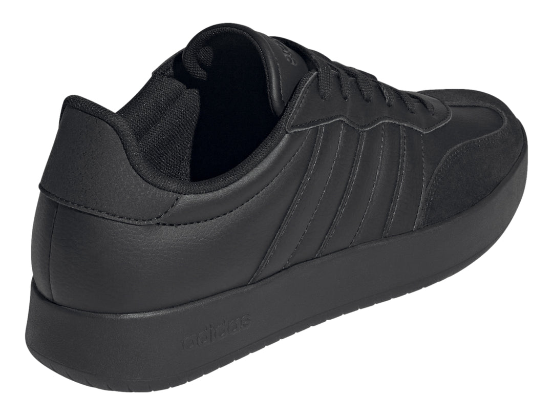 Tenis Adidas color negro con tres franjas laterales y suela plana.