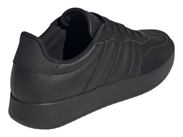 Tenis Adidas color negro con tres franjas laterales y suela plana.