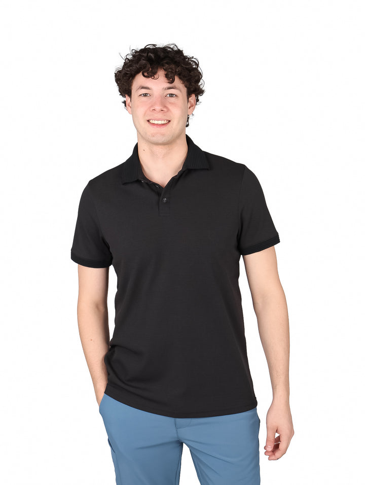 Hombre vistiendo una playera polo de color negro de manga corta.