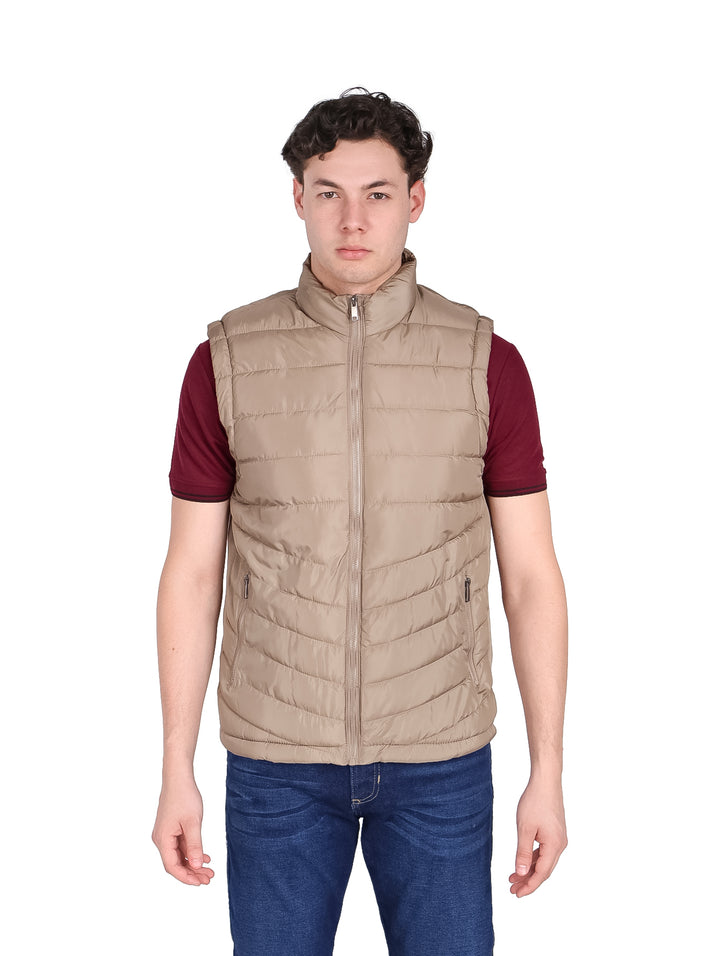 Hombre vistiendo un chaleco acolchado color beige con cierre frontal y cuello alto.