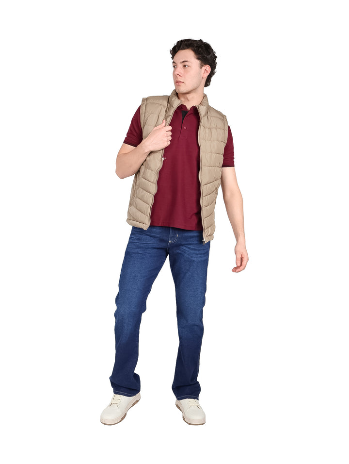 Hombre vistiendo un chaleco acolchado color beige con cierre frontal y cuello alto.