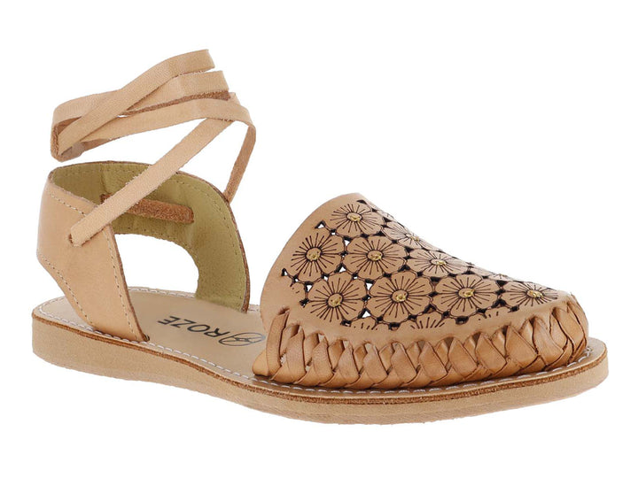 Sandalia plana color tan con diseño floral calado, frente trenzado y tiras largas para amarrar al tobillo.
