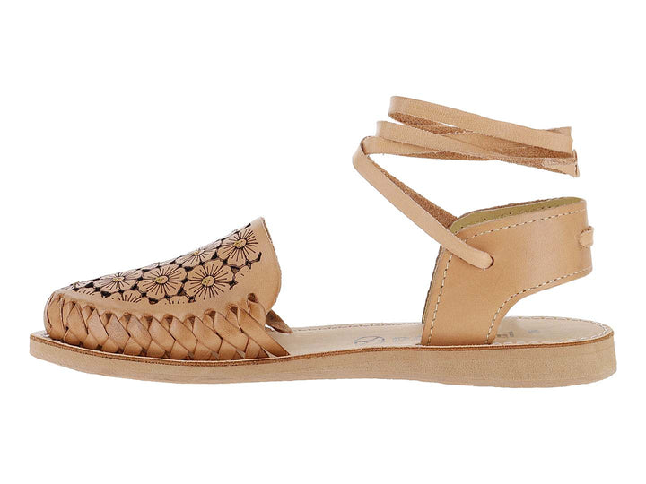 Sandalia plana color tan con diseño floral calado, frente trenzado y tiras largas para amarrar al tobillo.