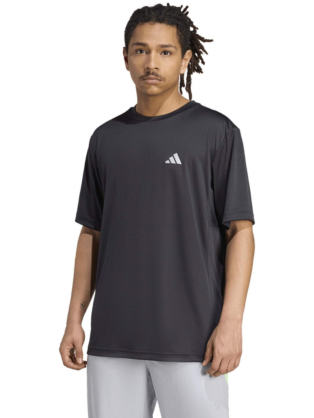 Hombre vistiendo una camiseta deportiva Adidas de color negro con logo blanco en el pecho.