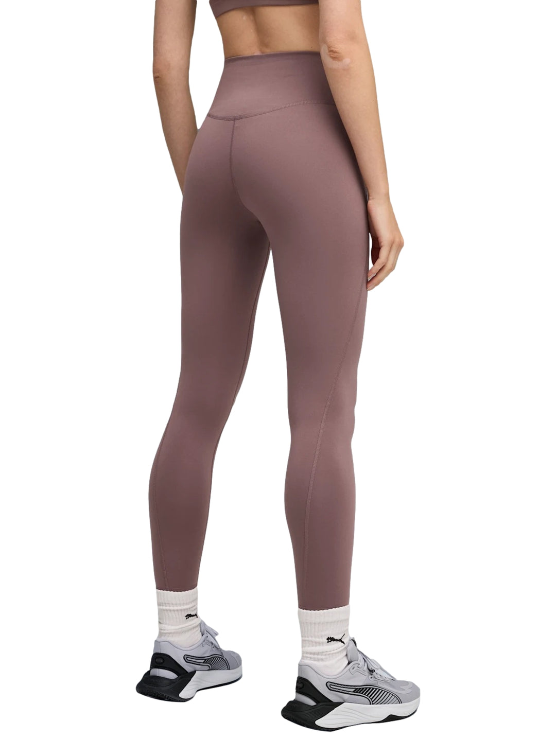 Mujer vistiendo leggings deportivos PUMA de color raisin con cintura alta.
