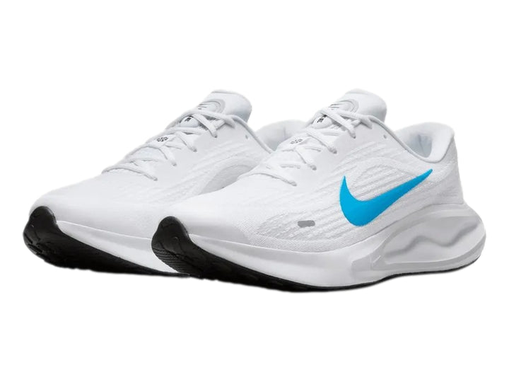 Tenis Nike Journey Run color blanco con logotipo azul y suela blanca y negra.