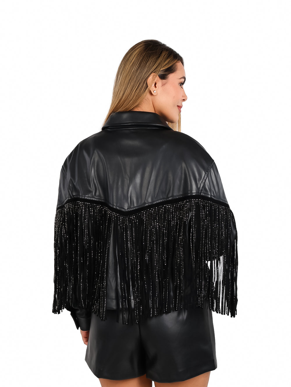 Mujer vistiendo chaqueta de vinipiel negra con flecos laterales y botones frontales.