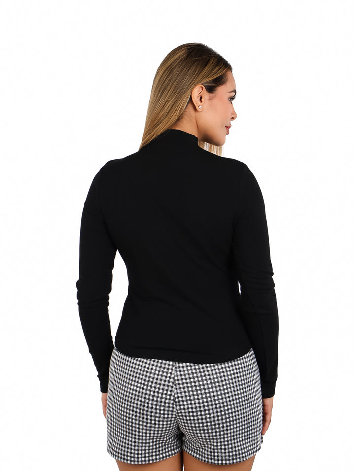 Mujer vistiendo una blusa negra ajustada de manga larga y cuello alto.