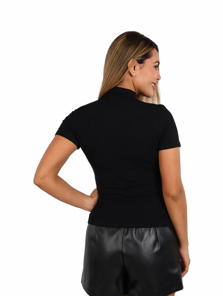 Mujer vistiendo una blusa negra de manga corta y cuello alto, combinada con shorts negros.