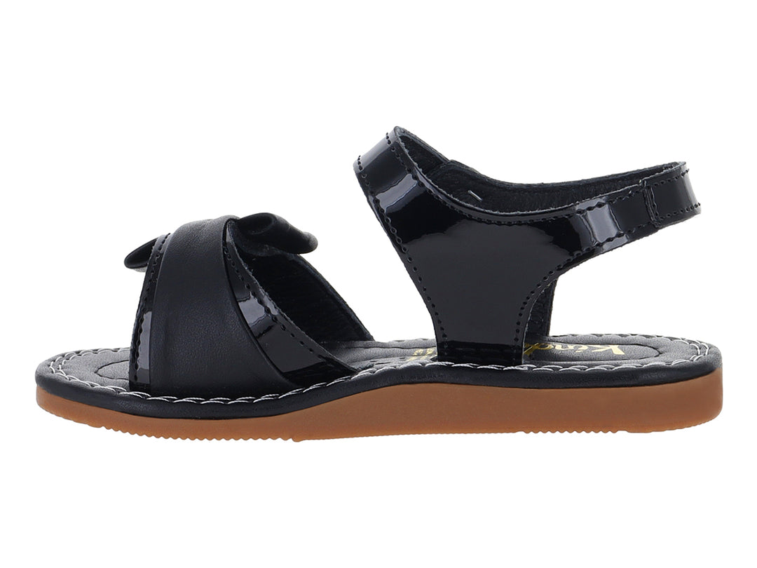 Sandalia de charol negro para niña con moño decorativo y suela color café.