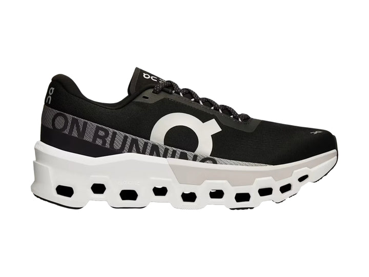 Tenis deportivos On Cloudmonster 2 color negro con suela blanca gruesa y diseño moderno.