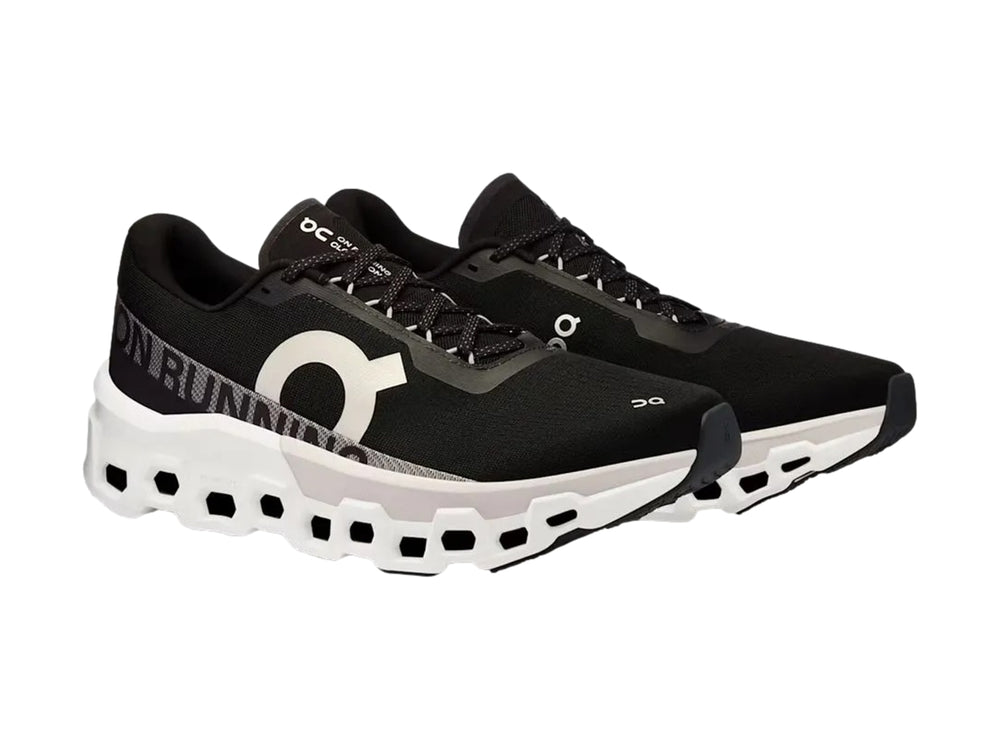 Tenis deportivos On Cloudmonster 2 color negro con suela blanca gruesa y diseño moderno.