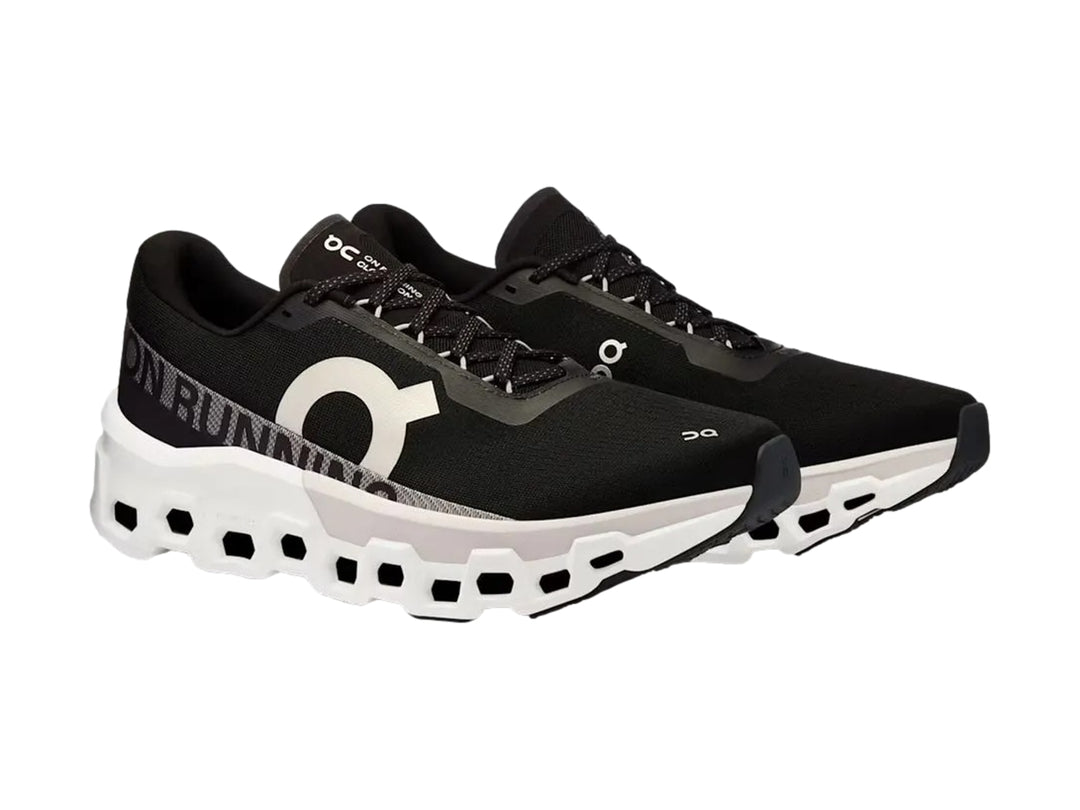 Tenis deportivos On Cloudmonster 2 color negro con suela blanca gruesa y diseño moderno.