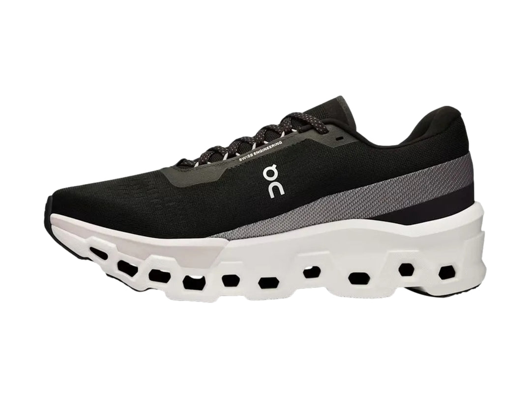 Tenis deportivos On Cloudmonster 2 color negro con suela blanca gruesa y diseño moderno.