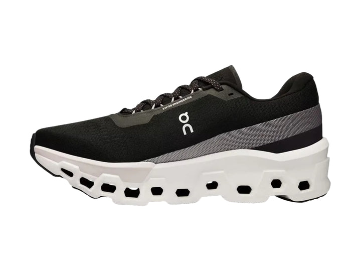 Tenis deportivos On Cloudmonster 2 color negro con suela blanca gruesa y diseño moderno.