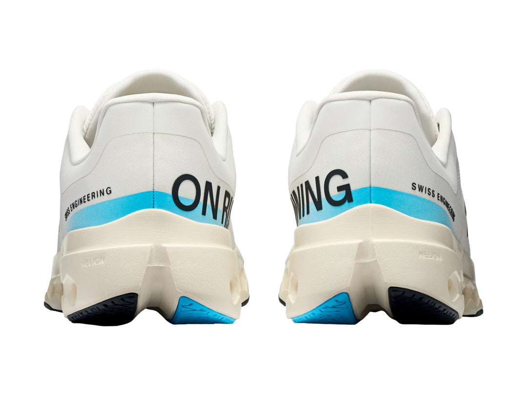Tenis deportivos On Cloud color ivory con detalles en azul y suela blanca con perforaciones.