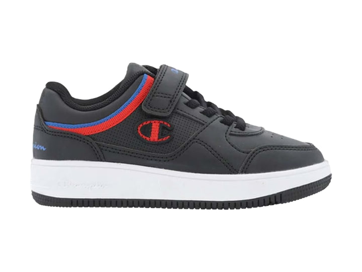 Tenis Champion negros con suela blanca, detalles en rojo y azul, y correa de ajuste.