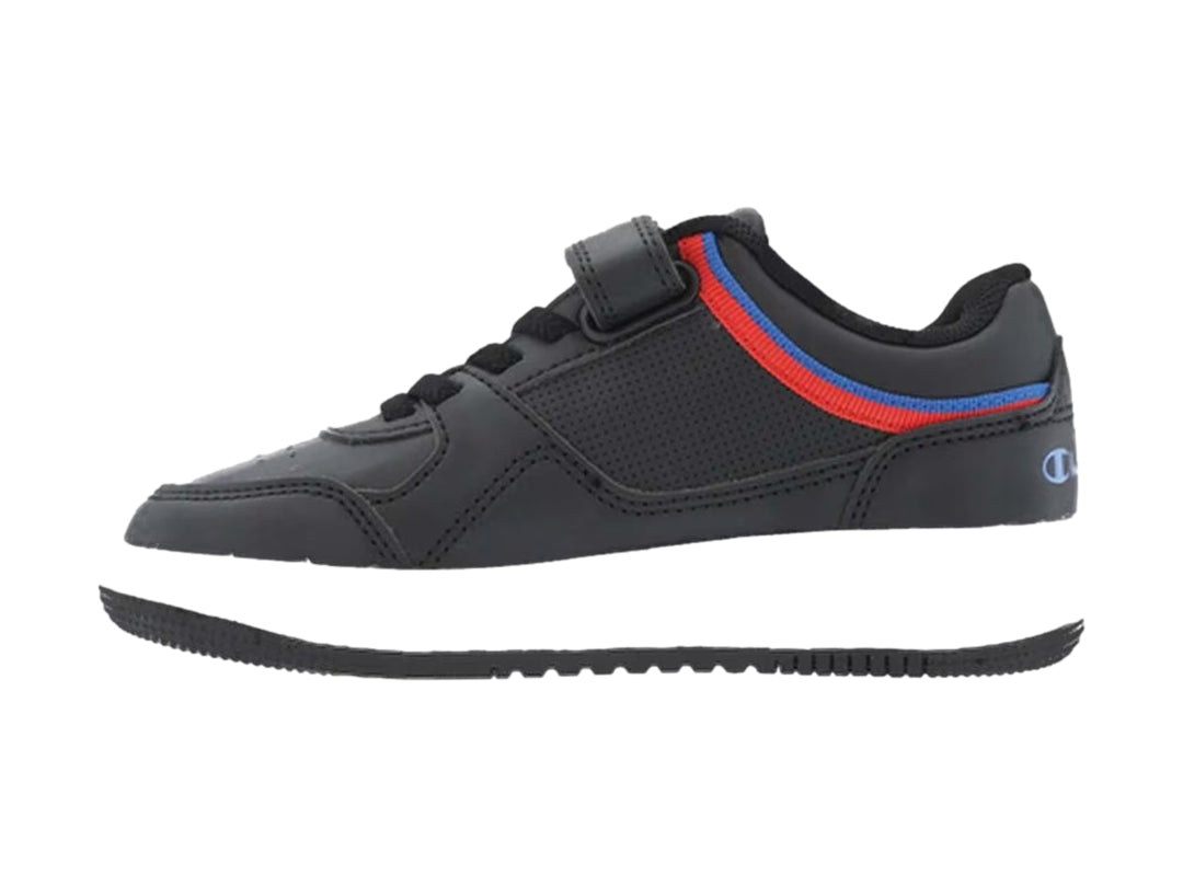 Tenis Champion negros con suela blanca, detalles en rojo y azul, y correa de ajuste.