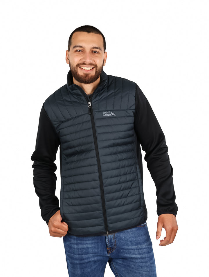 Hombre vistiendo chamarra híbrida Eddie Bauer color storm con chaleco acolchado y mangas negras.