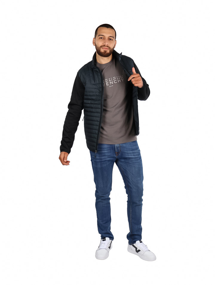 Hombre vistiendo chamarra híbrida Eddie Bauer color storm con chaleco acolchado y mangas negras.