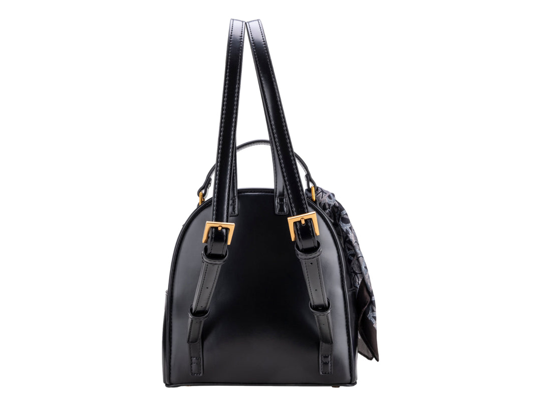 Mochila negra Cloe con herraje dorado y un pañuelo decorativo gris atado al asa superior.