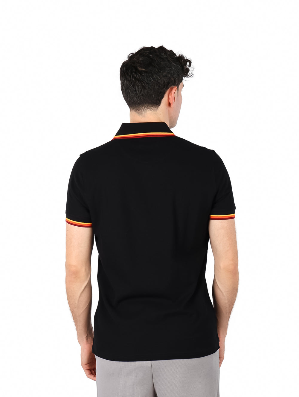 Hombre vistiendo polo negro de Givenchy con detalles de rayas coloridas en el cuello y los bordes de las mangas.