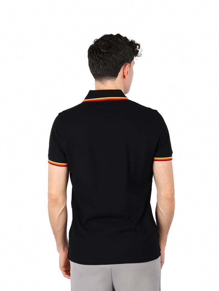 Hombre vistiendo polo negro de Givenchy con detalles de rayas coloridas en el cuello y los bordes de las mangas.