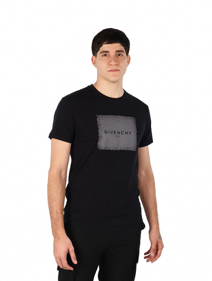 Hombre vistiendo una camiseta negra de manga corta con un estampado cuadrado gris de Givenchy en el pecho.