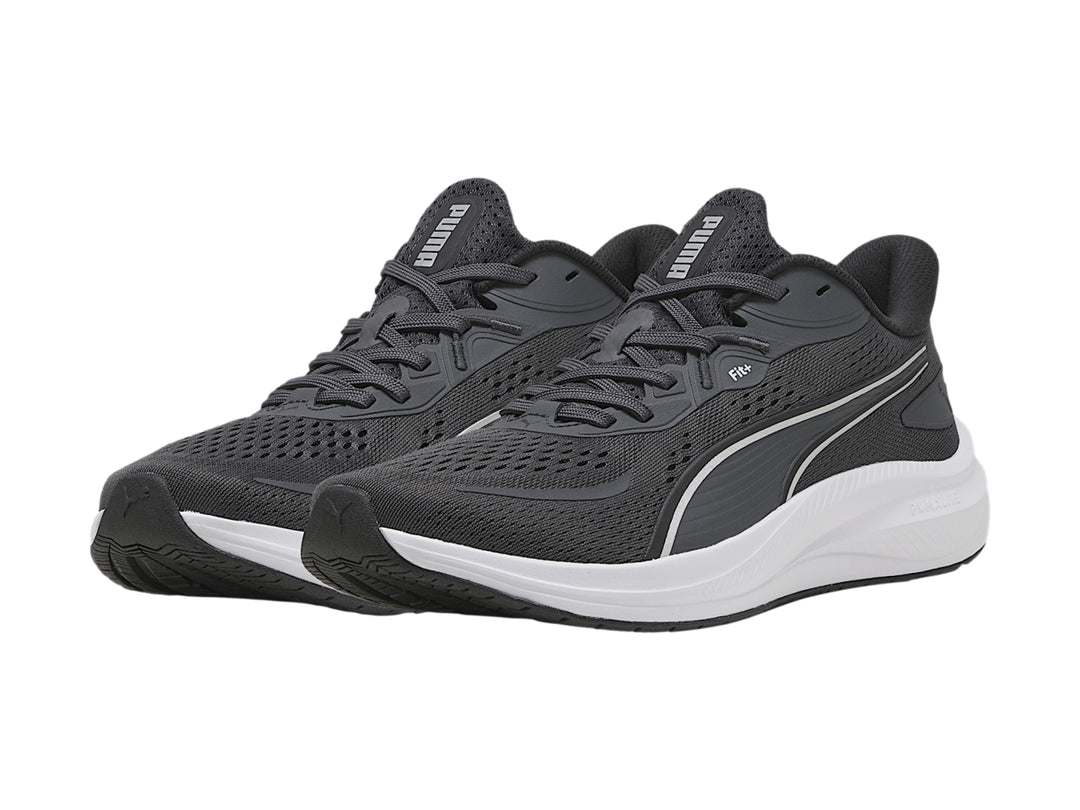 Tenis deportivos PUMA en color gris oscuro con suela blanca y franja plateada lateral.