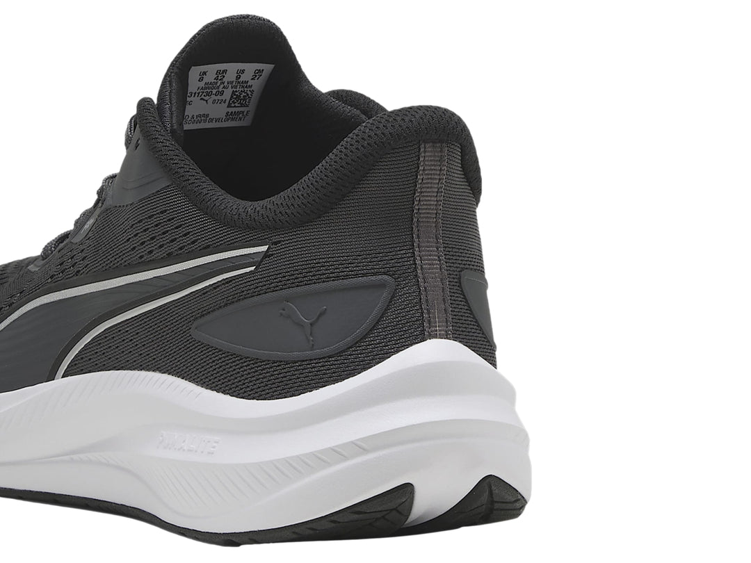 Tenis deportivos PUMA en color gris oscuro con suela blanca y franja plateada lateral.