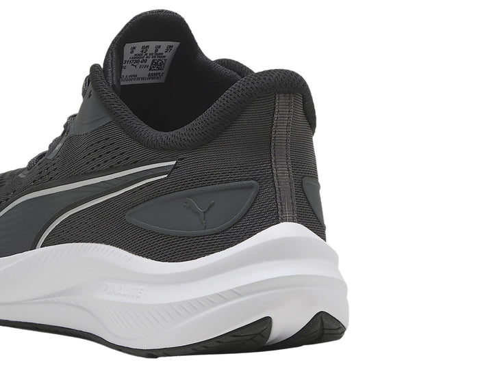 Tenis deportivos PUMA en color gris oscuro con suela blanca y franja plateada lateral.