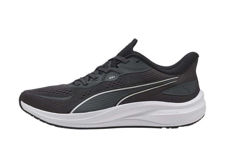 Tenis deportivos PUMA en color gris oscuro con suela blanca y franja plateada lateral.