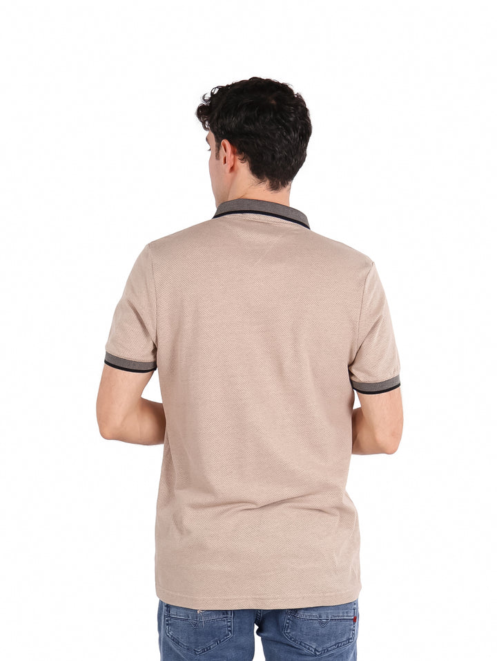 Hombre vistiendo playera polo color khaki con detalles en gris oscuro en el cuello y mangas.