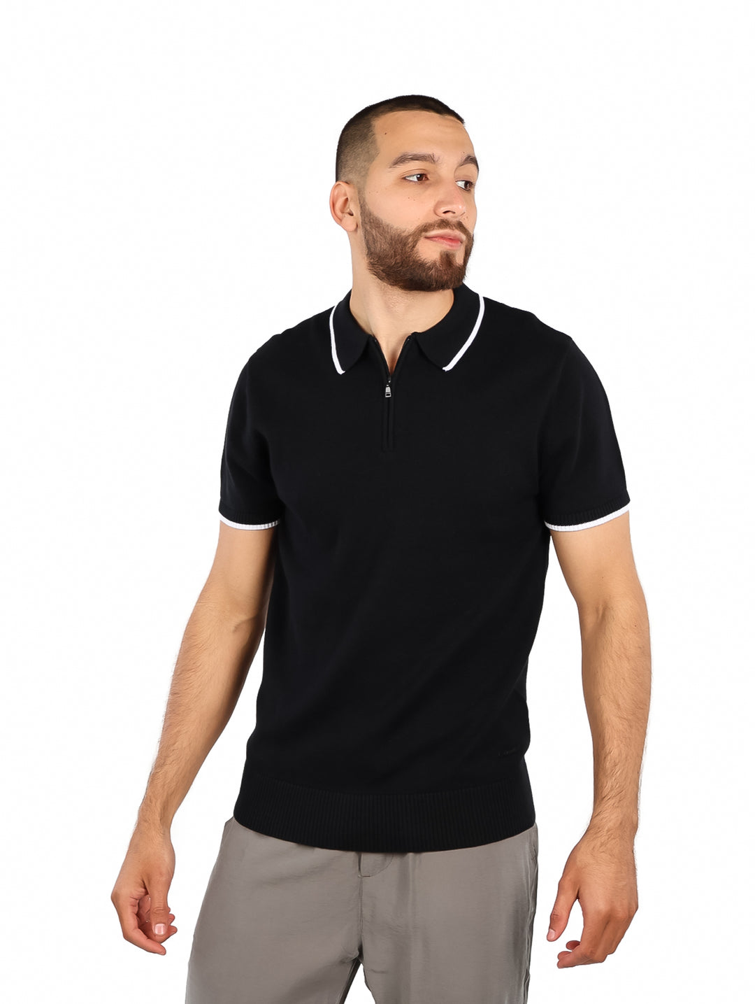 Hombre vistiendo polo negro de tejido con detalles blancos en el cuello y mangas.