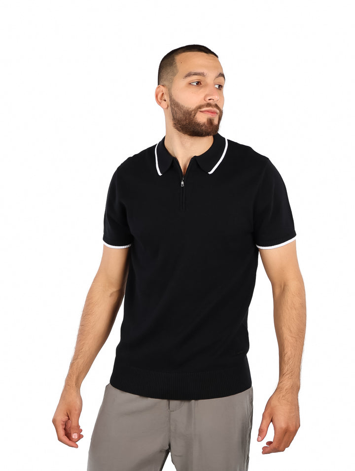 Hombre vistiendo polo negro de tejido con detalles blancos en el cuello y mangas.