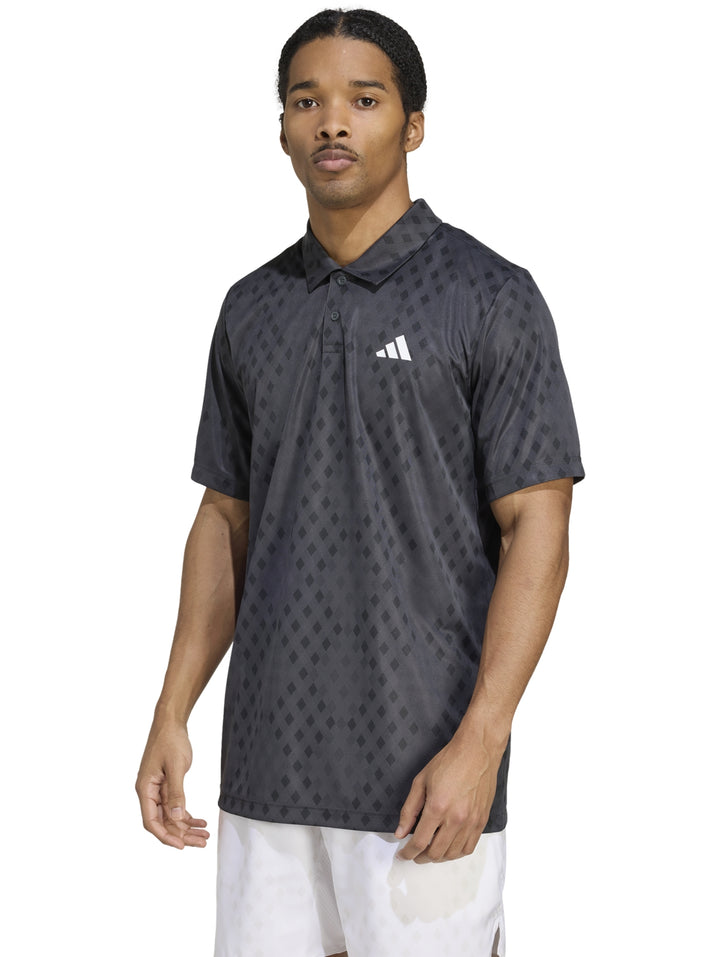 Hombre vistiendo polo deportivo Adidas color gris oscuro con patrón geométrico de diamantes.