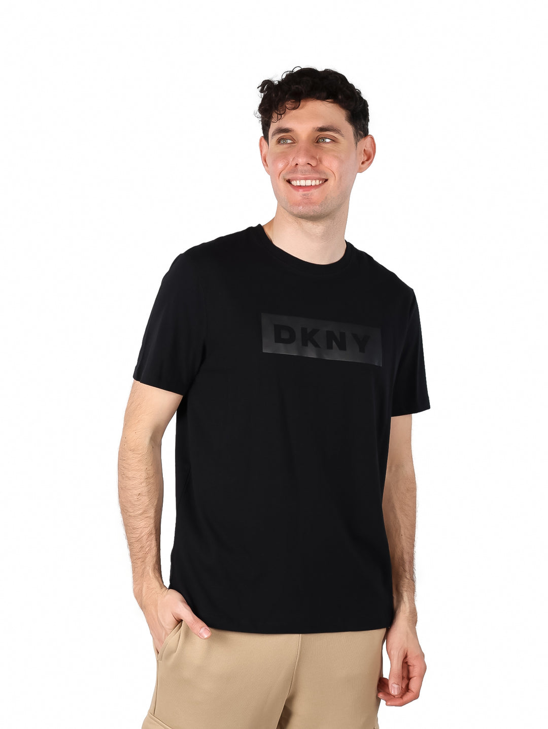 Hombre vistiendo una camiseta negra de manga corta con logotipo DKNY en el pecho.