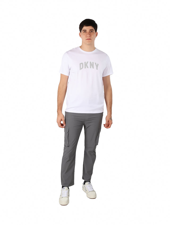 Hombre vistiendo una camiseta blanca de manga corta con el logo DKNY en el pecho.