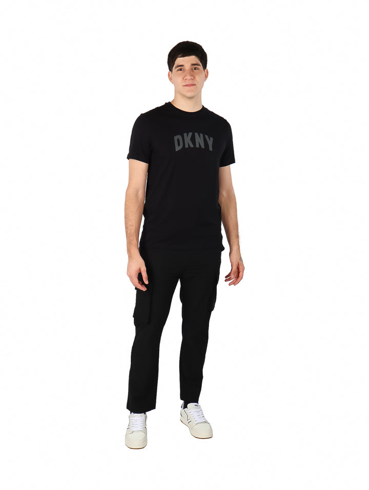 Hombre vistiendo una camiseta negra de manga corta con el logotipo de DKNY en el pecho.