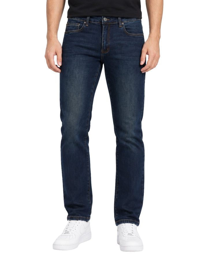 Hombre vistiendo jeans rectos de color índigo con calzado blanco sobre fondo blanco.